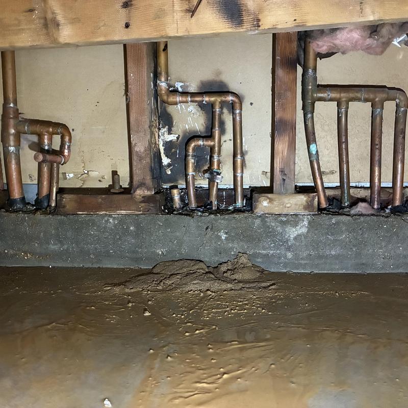 Copper plumbing pipes with burn and water damage in wall cavity