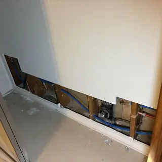 Cold water plumbing lines behind removed drywall panel