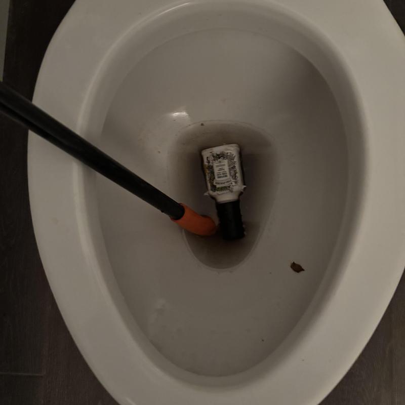 Toilet trap with clogged bottle and auger tool