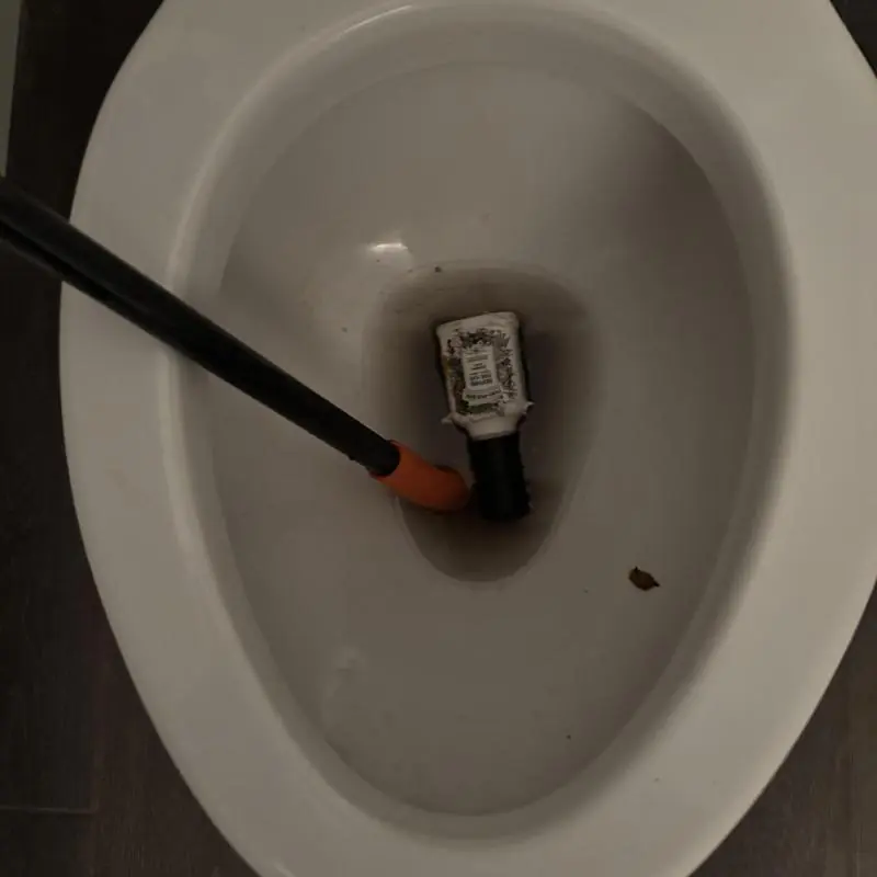 Toilet trap with clogged bottle and auger tool