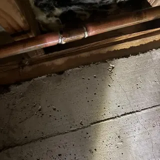 Copper water pipe under home with repaired joint
