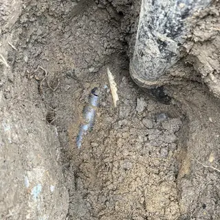 Main sewer line pipe break exposed in dirt excavation