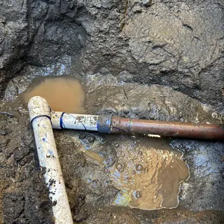2-inch water main pipe leak in muddy trench